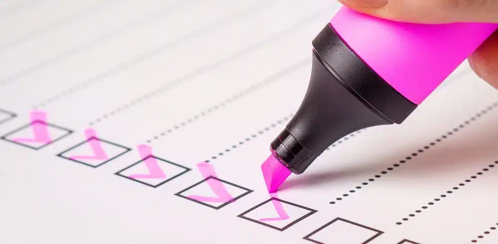 Close-up of a hand highlighting checkboxes on a pre-open house checklist, symbolizing the thorough preparation by realtors.