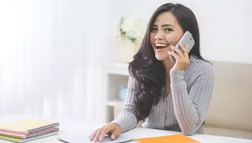 Smiling real estate agent engaged in a cold call conversation, showcasing effective communication for client prospecting.