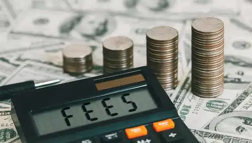 From Attorney to Agent: Why I Chose an eXp Realty Career 1 Calculator with the word 'FEES' on the display, surrounded by U.S. currency and coin stacks, depicting realtor expenses.